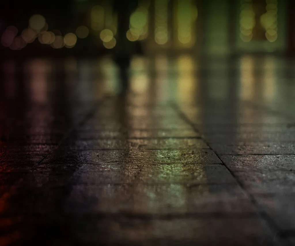 A wet pavement with blurry lights in the background